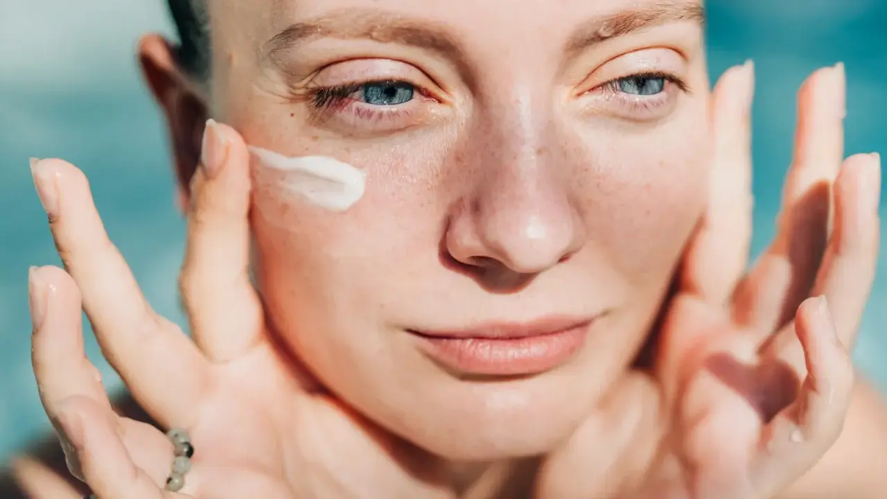 Donna applica crema sul viso. Attenzione: crema solare tutti i giorni fa male alla pelle.