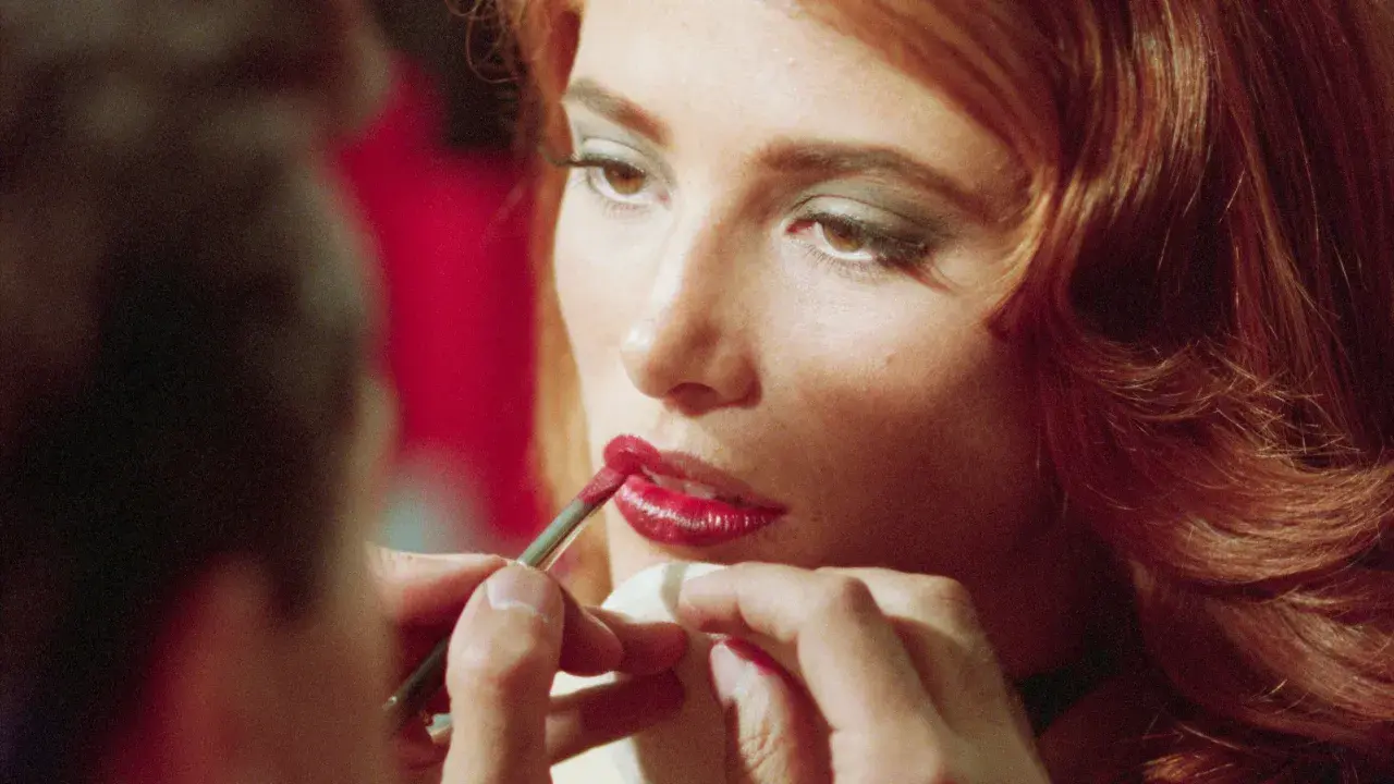 Dettagli di un trucco labbra perfetto: un pennellino applica rossetto rosso brillante, un segreto per non far sbavare il rossetto.
