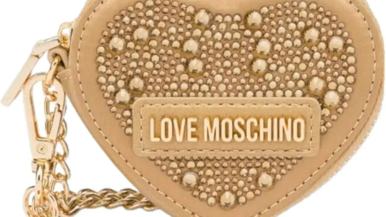 A beige heart-shaped Moschino keychain with gold studs and "LOVE MOSCHINO" logo.