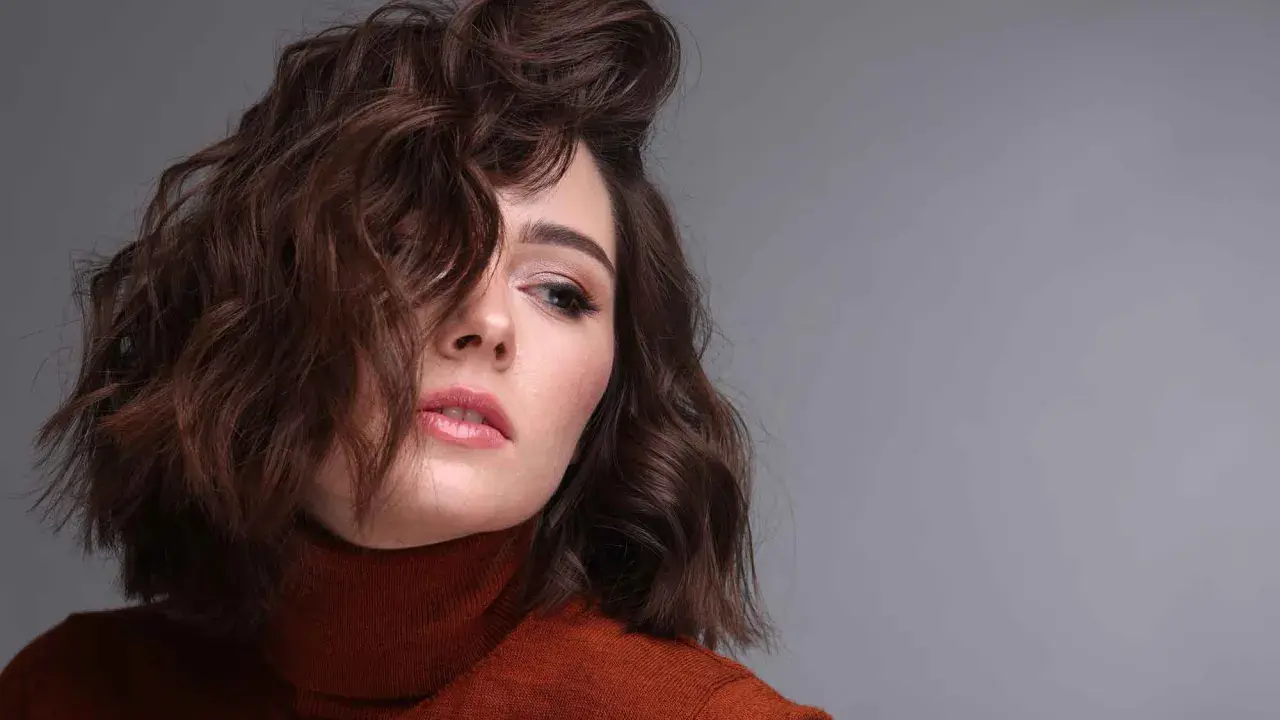 Modella con capelli castani mossi, un look ispirato a come fare i capelli mossi con onde morbide e naturali.