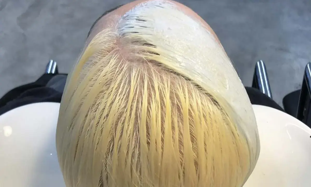 Applicazione di una maschera schiarente per un trattamento capelli decolorati. La chioma bionda è pronta per essere trasformata.