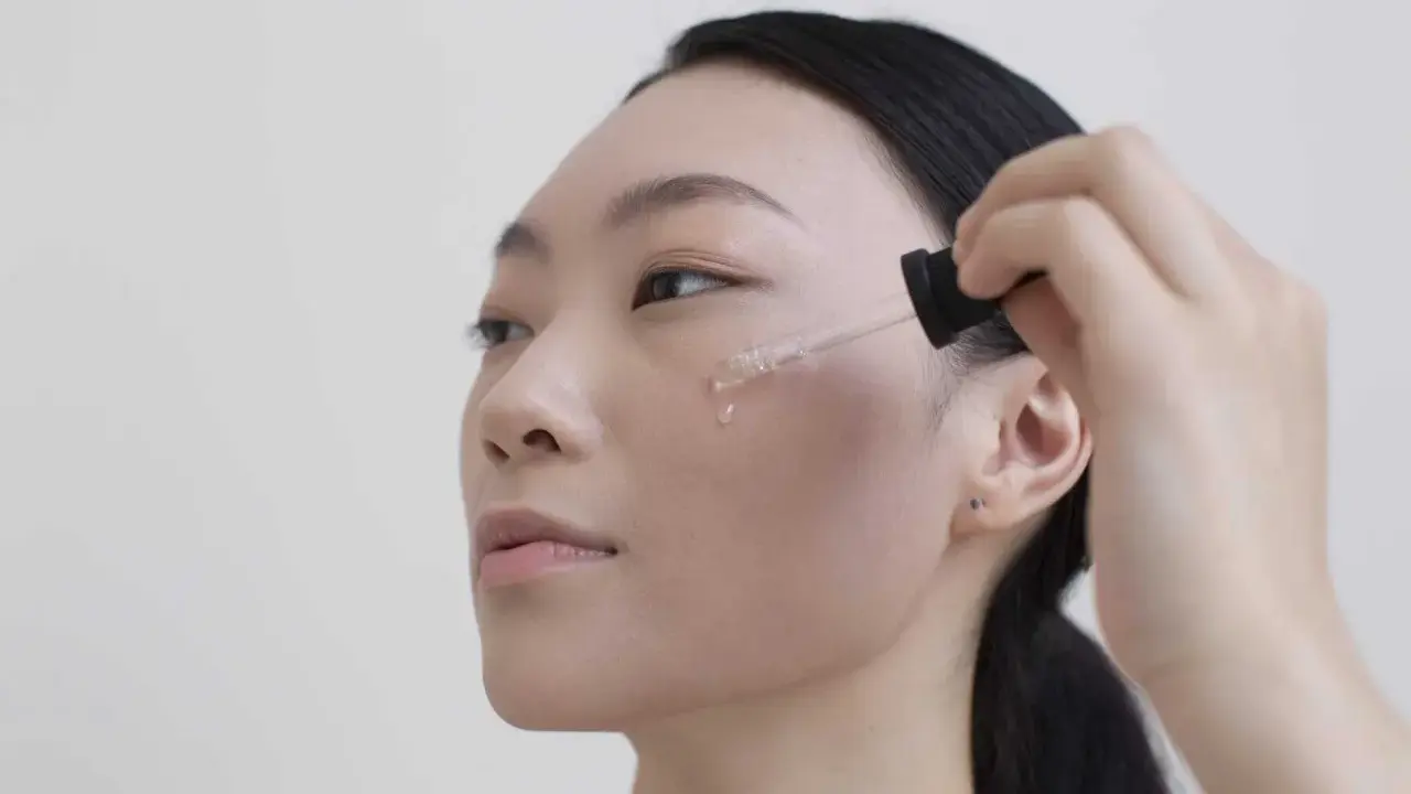 Donna applica siero viso. Per sapere niacinamide dopo quanto fa effetto, guarda la sua pelle luminosa.