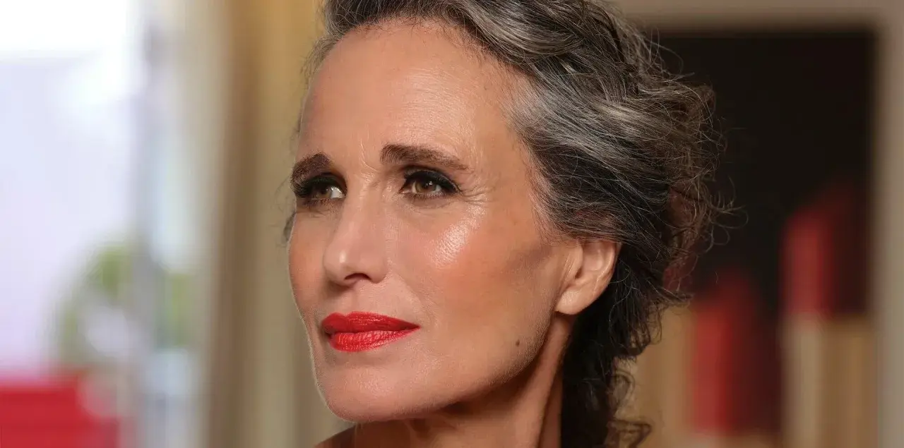 Donna con capelli grigi e trucco impeccabile, labbra rosse vivaci. Un esempio di come truccarsi a 50 anni con eleganza.