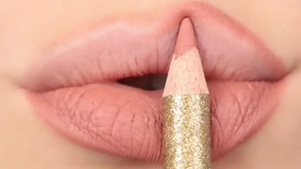 Matita glitterata color oro definisce il contorno delle labbra con un tratto preciso, creando un effetto overline labbra impeccabile.