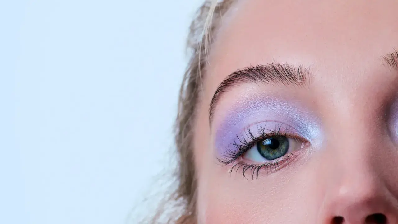 Occhio con ombretto lilla scintillante, ciglia lunghe e sopracciglia definite. Un trucco per serata elegante che cattura lo sguardo.
