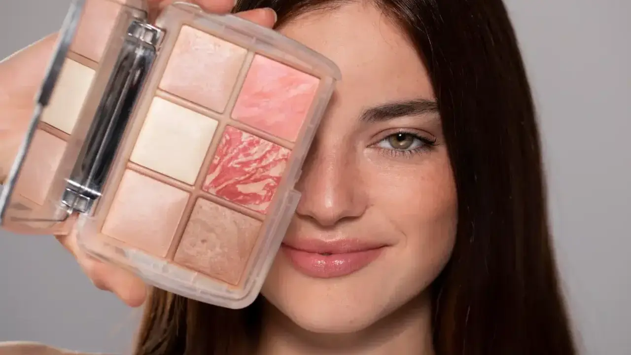 Una donna sorride mostrando una palette di make up elegante con sei cialde di diverse tonalità rosate e luminose.