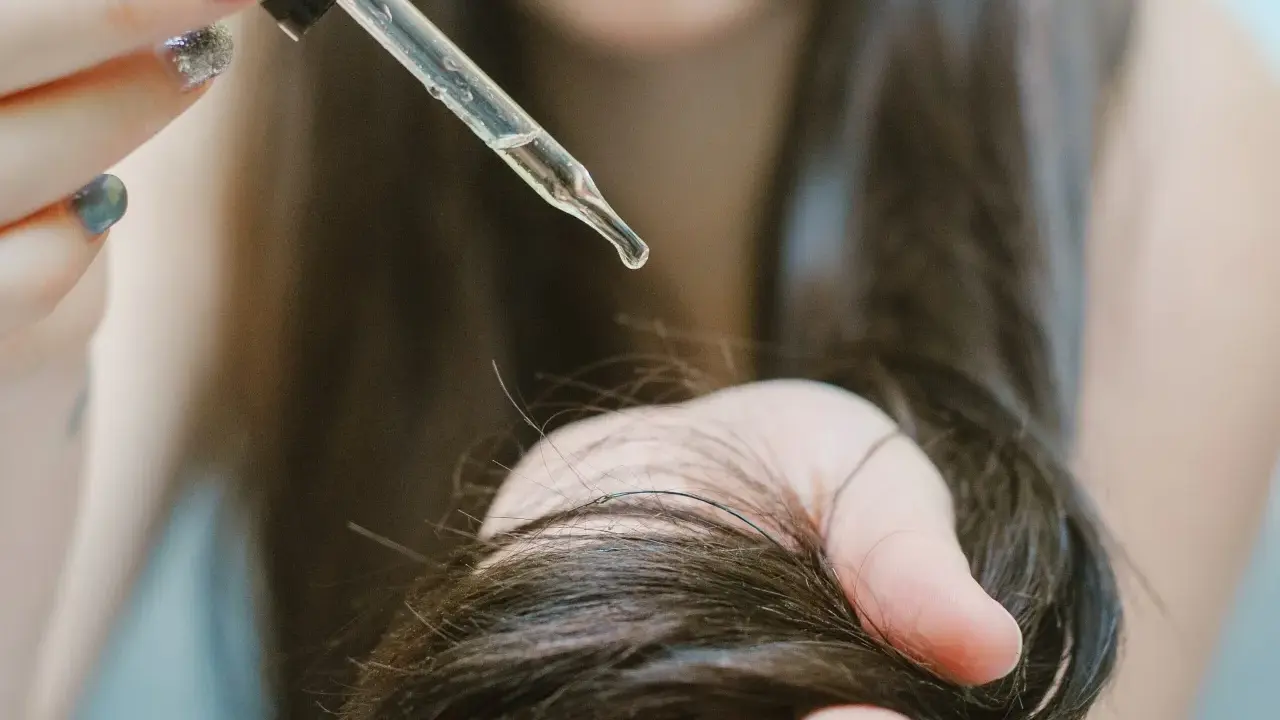 Goccia di olio di ricino su capelli scuri. Scopri a cosa serve l'olio di ricino per la cura dei capelli e della pelle.