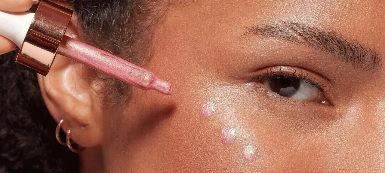 Gocce di illuminante rosa applicate sul viso con un contagocce, per un look radioso.