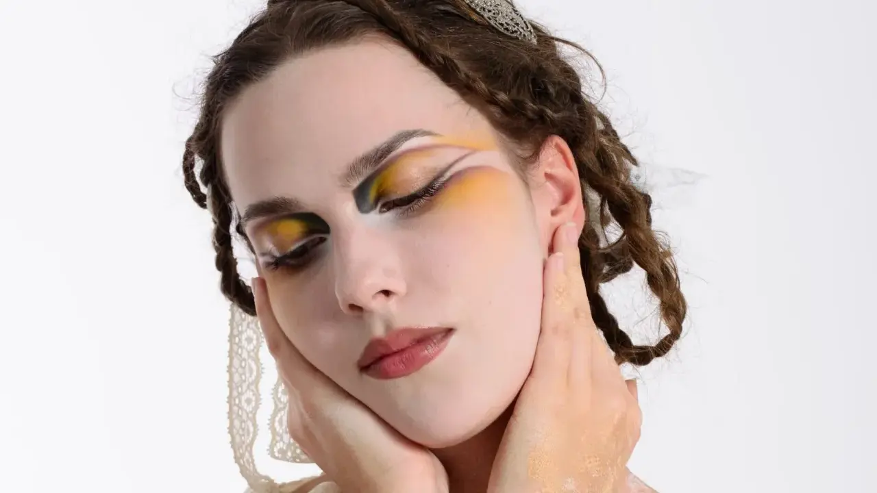 Modella con trucco artistico audace, occhi colorati e dettagli dorati. Idee trucco artistico per un look da sogno.