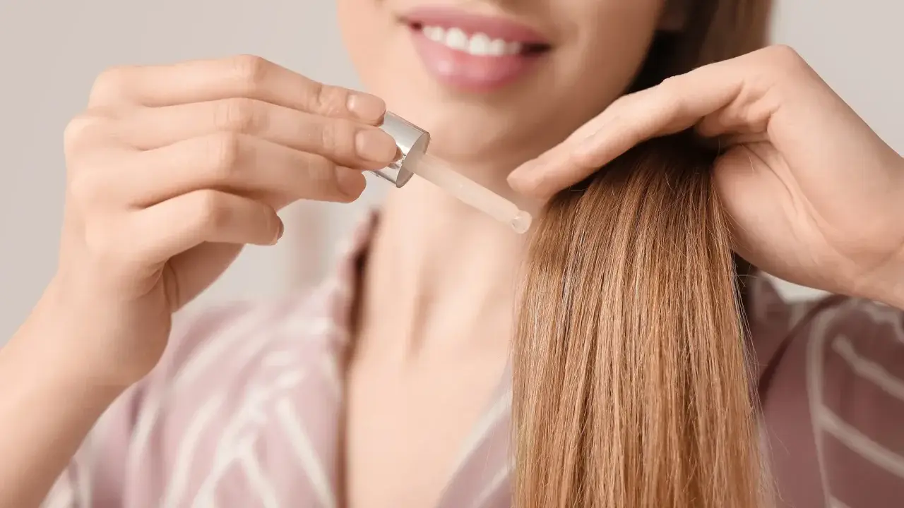 Una donna applica olio di oliva sui capelli decolorati per nutrirli e renderli lucenti.
