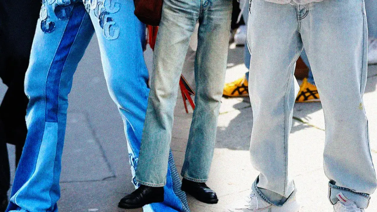 Gambe in primo piano con diversi modelli di moschino jeans: uno blu con inserti e ricami, uno più chiaro e sbiadito, e uno grigio chiaro oversize.