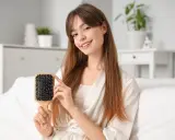 Ragazza sorridente mostra una spazzola per capelli in plastica, perfetta per districare e pulire i capelli.