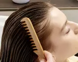Una mano pettina delicatamente i capelli bagnati, sciogliendo eventuali nodi ai capelli dietro la nuca per una chioma fluente.
