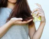 Donna applica olio di jojoba sui capelli, sfruttando le sue proprietà nutrienti per una chioma sana e lucente.