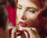 Dettagli di un trucco labbra perfetto: un pennellino applica rossetto rosso brillante, un segreto per non far sbavare il rossetto.