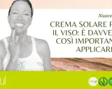 Donna sorridente applica crema sul viso. Il blog parla di crema solare per il viso: è davvero importante usarla come crema idratante?