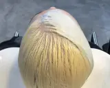 Applicazione di una maschera schiarente per un trattamento capelli decolorati. La chioma bionda è pronta per essere trasformata.