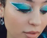 Occhi con ombretto blu elettrico e strass scintillanti, un look che fa make up euphoria. Orecchino pendente con cristallo.