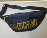 Borsa blu Moschino con logo dorato in rilievo, tracolla regolabile e zip. Un accessorio iconico per un look audace.