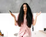 Donna con capelli elettrizzati e spazzola in mano, espressione sorpresa.