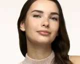 Primo piano di una giovane donna con lentiggini, labbra lucide e sopracciglia definite. Un look naturale, perfetto come trucco da fare per ogni occasione.