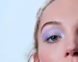 Occhio con ombretto lilla scintillante, ciglia lunghe e sopracciglia definite. Un trucco per serata elegante che cattura lo sguardo.