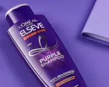 Flacone di shampoo viola L'Oréal Elseve Color-Vive, con auricolari e quaderno viola. Lo shampoo antigiallo schiarisce i capelli, neutralizzando i toni indesiderati.