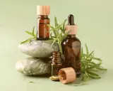 Flaconi ambrati con gocce e rametti di rosmarino, che evocano le proprietà dell'olio essenziale di rosmarino.