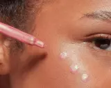 Gocce di illuminante rosa applicate sul viso con un contagocce, per un look radioso.