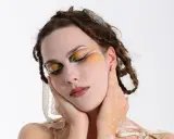 Modella con trucco artistico audace, occhi colorati e dettagli dorati. Idee trucco artistico per un look da sogno.