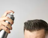 Mano che spruzza lacca sui capelli. Attenzione, la cera fa cadere i capelli, ma questo prodotto è per fissare.