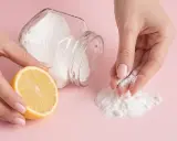 Mani che preparano una maschera fai-da-te con limone e bicarbonato per scoprire come togliere i brufoli dal viso.