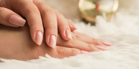 Mani curate con smalto rosa tenue, un esempio di come nutrire le unghie per una bellezza impeccabile.