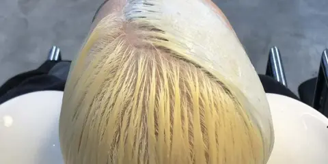 Applicazione di una maschera schiarente per un trattamento capelli decolorati. La chioma bionda è pronta per essere trasformata.