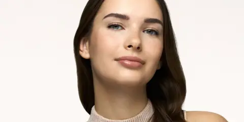 Primo piano di una giovane donna con pelle luminosa e lentiggini, un naturale effetto bonne mine.