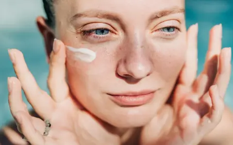 Donna applica crema sul viso. Attenzione: crema solare tutti i giorni fa male alla pelle.