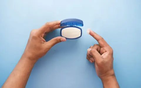 Mano che preleva vaselina per lenire l'irritazione da retinolo.
