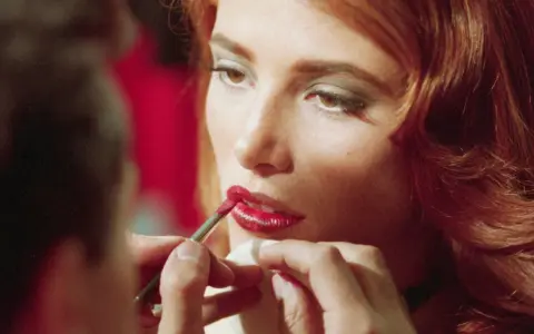 Dettagli di un trucco labbra perfetto: un pennellino applica rossetto rosso brillante, un segreto per non far sbavare il rossetto.