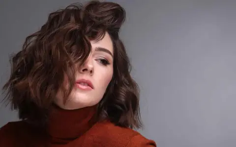 Modella con capelli castani mossi, un look ispirato a come fare i capelli mossi con onde morbide e naturali.
