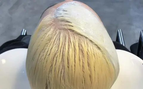 Applicazione di una maschera schiarente per un trattamento capelli decolorati. La chioma bionda è pronta per essere trasformata.