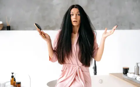 Donna con capelli elettrizzati e spazzola in mano, espressione sorpresa.