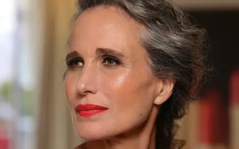Donna con capelli grigi e trucco impeccabile, labbra rosse vivaci. Un esempio di come truccarsi a 50 anni con eleganza.