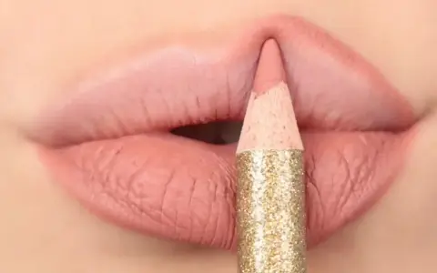 Matita glitterata color oro definisce il contorno delle labbra con un tratto preciso, creando un effetto overline labbra impeccabile.