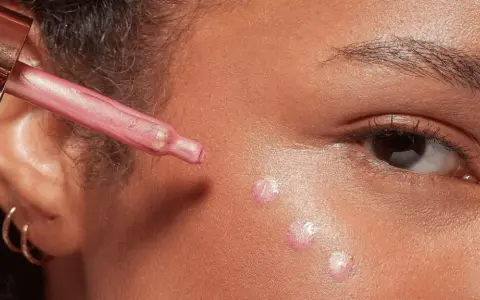 Gocce di illuminante rosa applicate sul viso con un contagocce, per un look radioso.