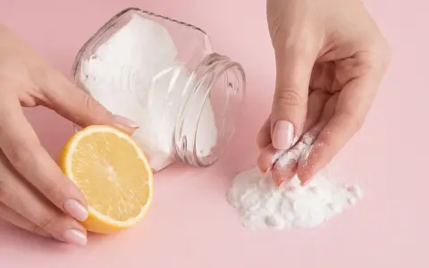 Mani che preparano una maschera fai-da-te con limone e bicarbonato per scoprire come togliere i brufoli dal viso.