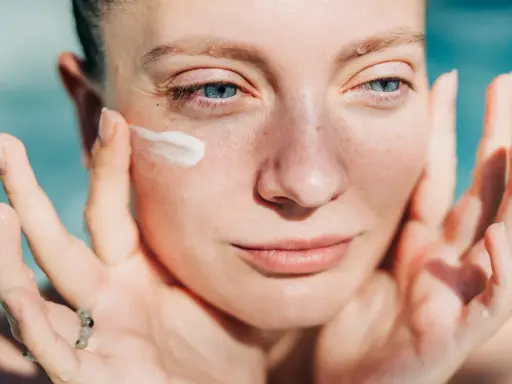 Donna applica crema sul viso. Attenzione: crema solare tutti i giorni fa male alla pelle.