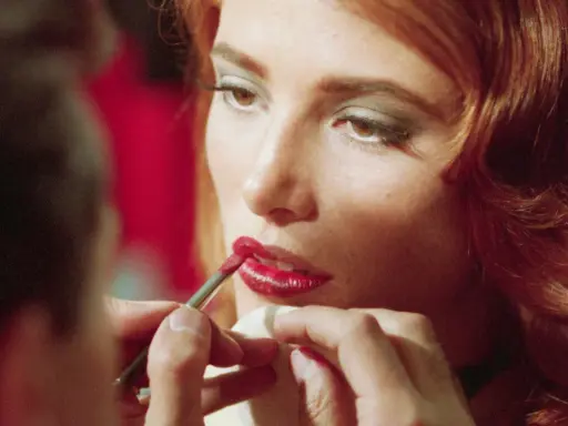 Dettagli di un trucco labbra perfetto: un pennellino applica rossetto rosso brillante, un segreto per non far sbavare il rossetto.