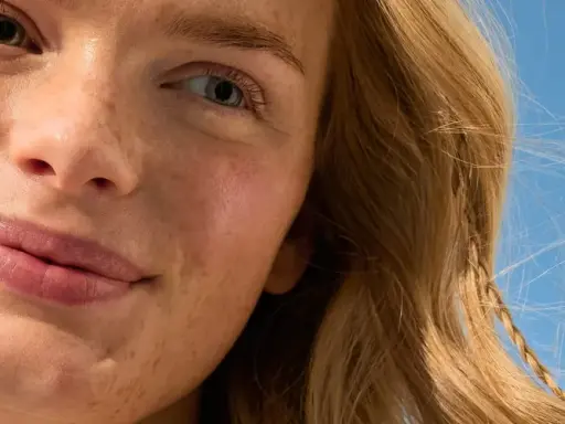 Viso sorridente con lentiggini, capelli biondi mossi dal vento. La sua pelle è protetta, una protezione 50 che dura 50 minuti sotto il sole.