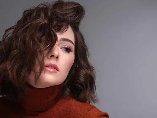 Modella con capelli castani mossi, un look ispirato a come fare i capelli mossi con onde morbide e naturali.