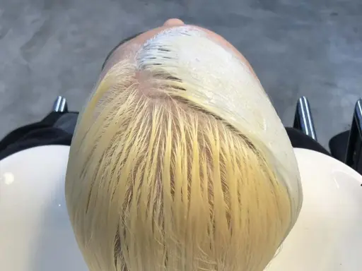 Applicazione di una maschera schiarente per un trattamento capelli decolorati. La chioma bionda è pronta per essere trasformata.